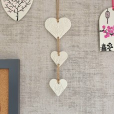 White clay hanging trio of hearts with peacock henna style design on natural twine.